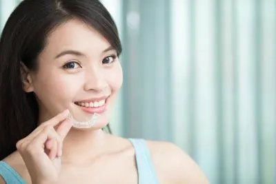 woman holding her Invisalign clear aligners